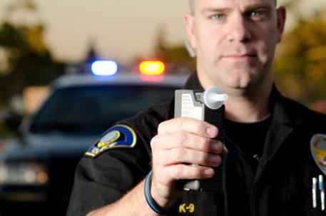 a police officer holds up a breathalyzer machine